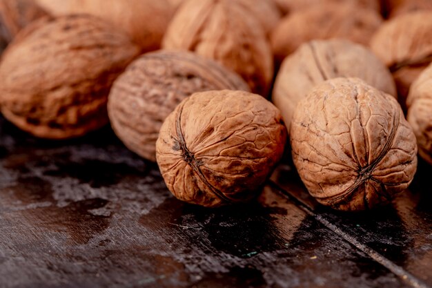 Side view of whole walnuts scattered on black wooden background