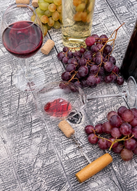 Вид сбоку бутылки вина с виноградом на белой деревянной вертикали