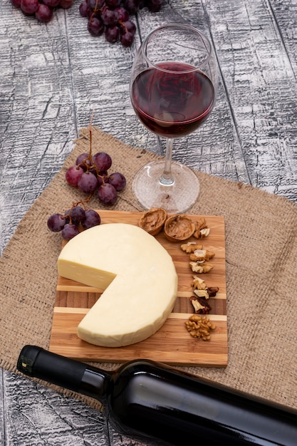 보드와 흰색 나무 수직에 포도와 치즈 측면보기 와인