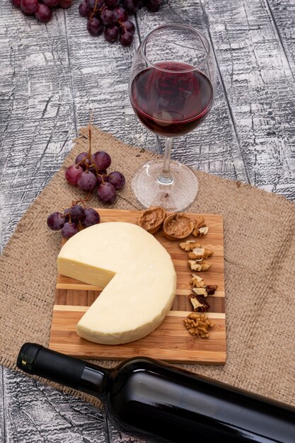 Side view wine with grape and cheese on board and on white wooden vertical