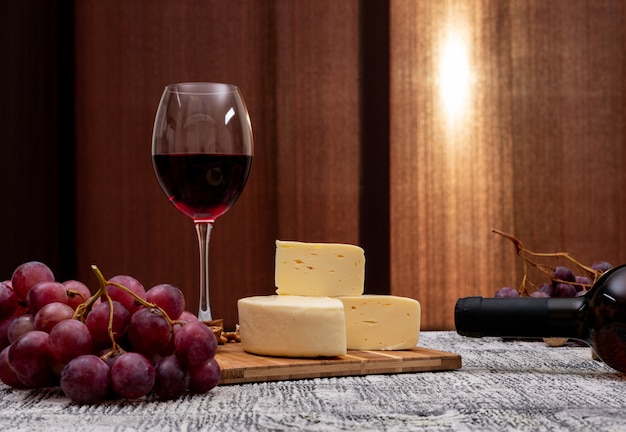 Foto gratuita vino di vista laterale con l'uva e formaggio sulla tavola di legno bianca e sull'orizzontale