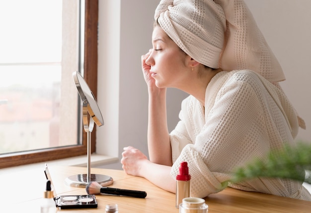 Side view woman applying eyeliner