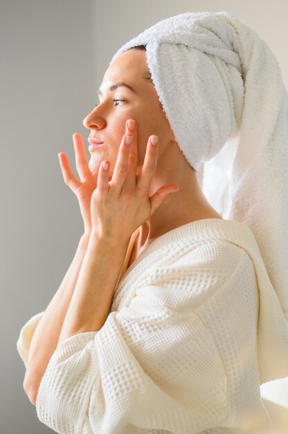 Side view of woman applying face cream at home