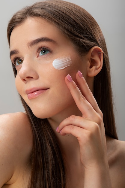 Free photo side view woman applying face cream