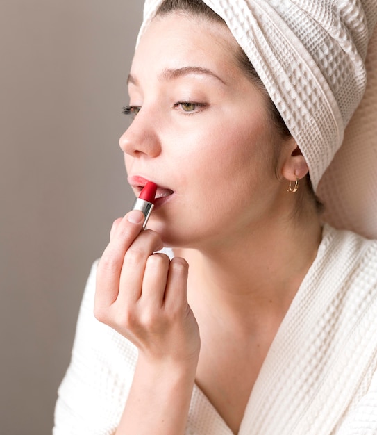 Free photo side view woman applying lipstick