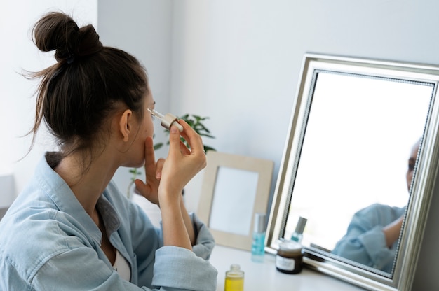 Free photo side view woman applying serum