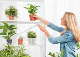 Foto gratuita donna di vista laterale che organizza il vaso di fiori