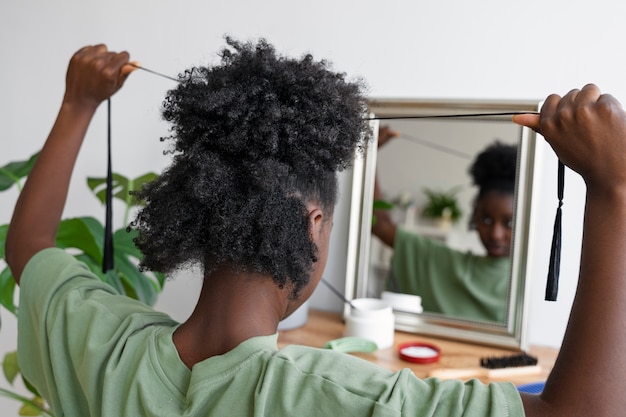 Free photo side view woman arranging hair in mirror