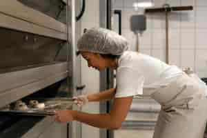 Free photo side view woman baking in kitchen