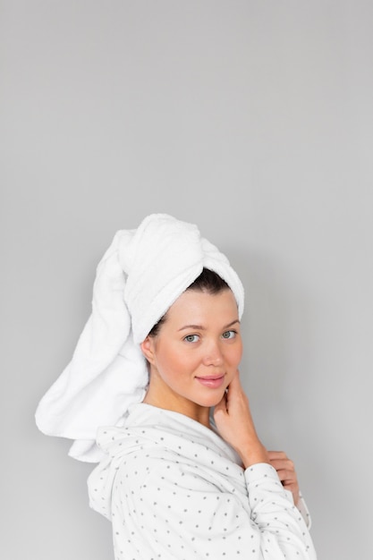 Вид сбоку женщины в халате и полотенце, показывающей красивое лицо