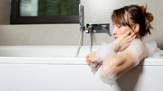 Side view woman in bathtub with foam