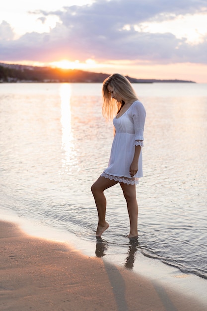 Foto gratuita vista laterale della donna in spiaggia al tramonto