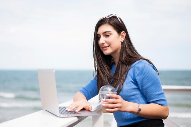 Side view of woman at the beach working on laptop