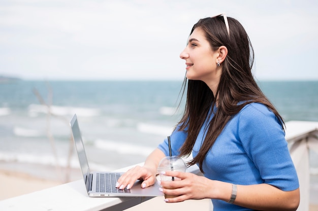 Side view of woman at the beach working on laptop