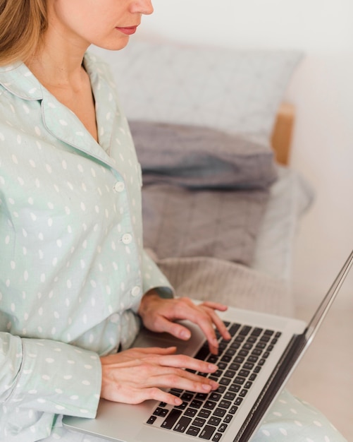 Free photo side view of woman in bed wearing pajamas and working