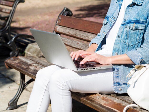 Side view of woman on bench working on laptop