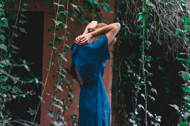 Side view woman buttoning dress near old house