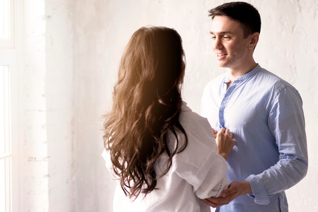 Free photo side view of woman buttoning man's shirt