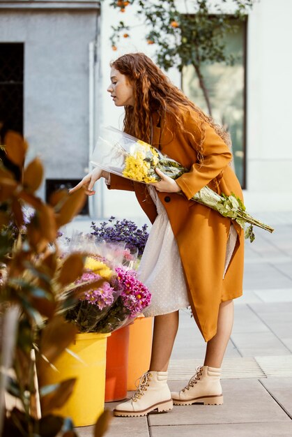 屋外で春の花を買う女性の側面図