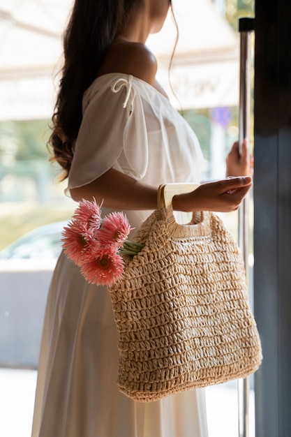 Side view woman carrying bag with flowers