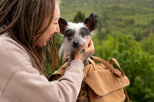 Free photo side view woman carrying dog in bag