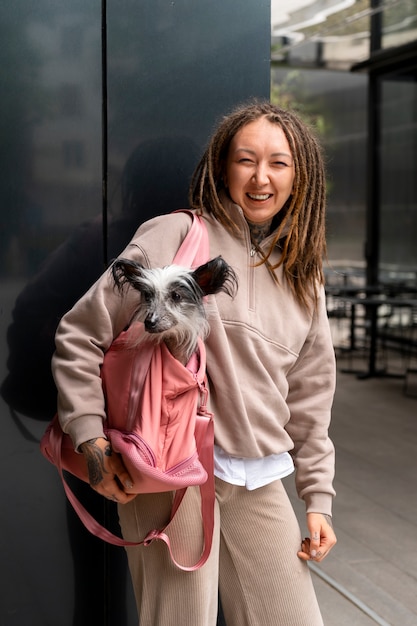 Free photo side view woman carrying dog in bag
