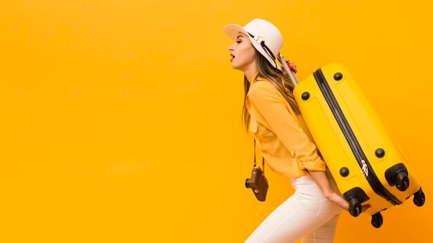 Side view of woman carrying luggage and camera