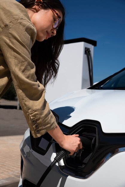 電気自動車を充電する側面図の女性