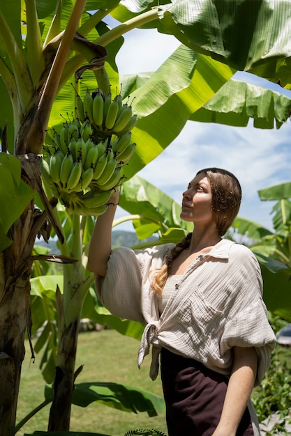Вид сбоку женщина проверяет банановое дерево