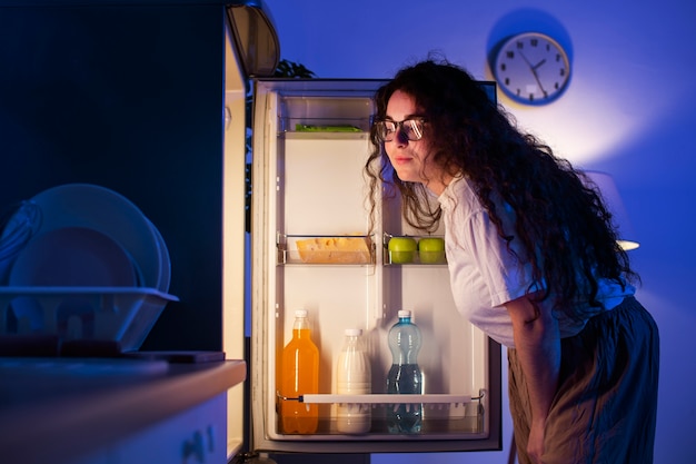 Free photo side view woman checking the fridge