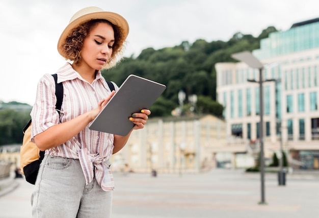 サイドビューの女性が彼女のタブレットの方向をチェック