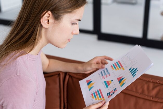 Side view woman checking some statistics on paper