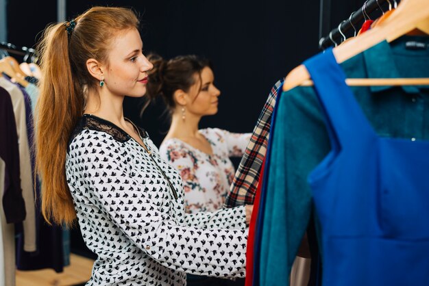 Вид сбоку женщина выбора одежды в магазине