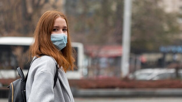 Side view of woman in the city wearing medical mask with copy space