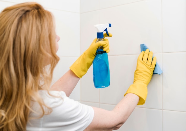 Side view of woman cleaning the shower wall