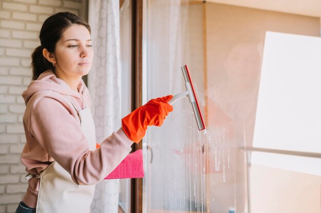 Side view woman cleaning window