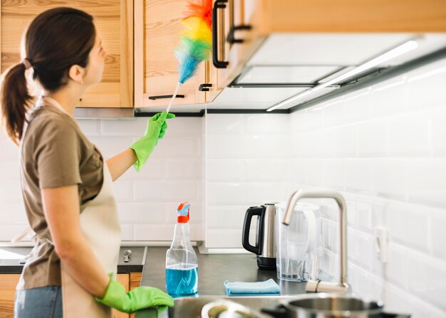 Side view woman cleaning with duster