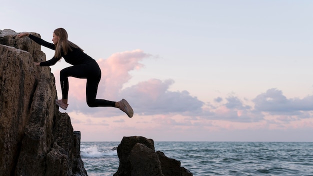 Side view woman climbing on a coast