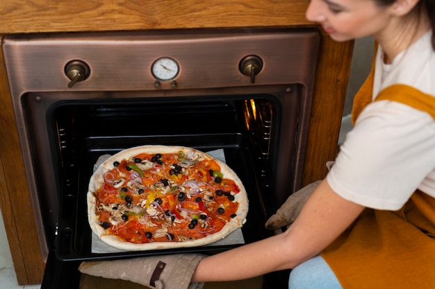 Free photo side view woman cooking pizza