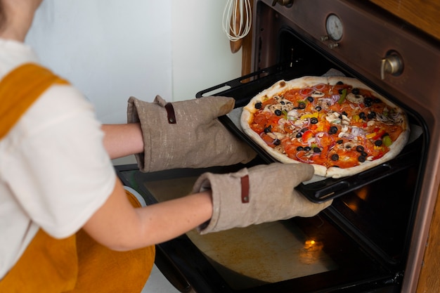 Foto gratuita donna di vista laterale che cucina pizza