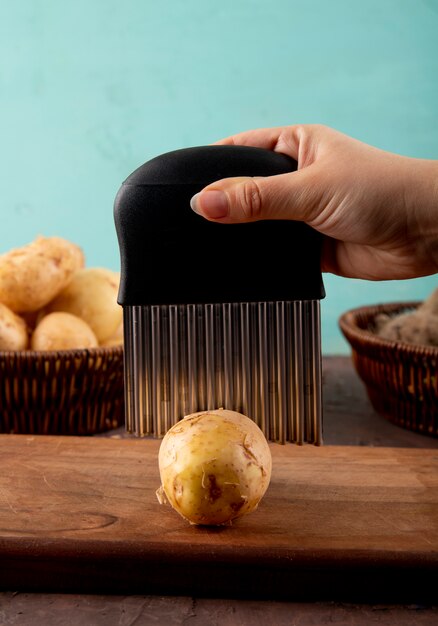 Side view woman cuts potatoes on a board with beetroot in a basket