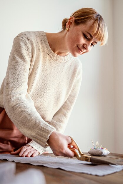 Side view woman cutting a fabric