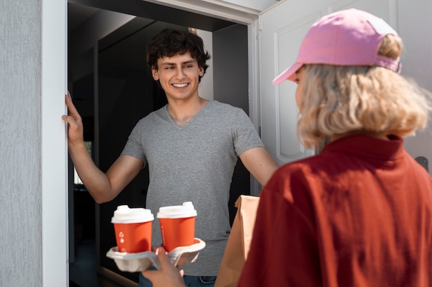 Free photo side view woman delivering coffee cups