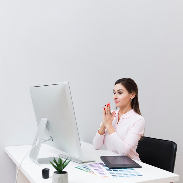 Вид сбоку женщины за столом, с тревогой глядя на компьютер
