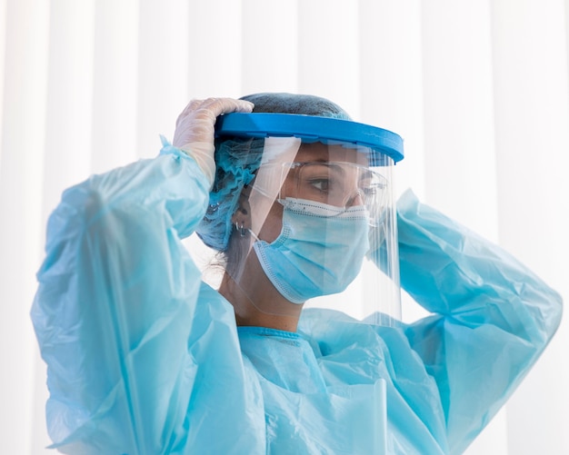 Side view woman doctor putting on protective wear