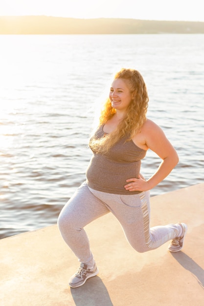 Free photo side view of woman doing lunges by the lake