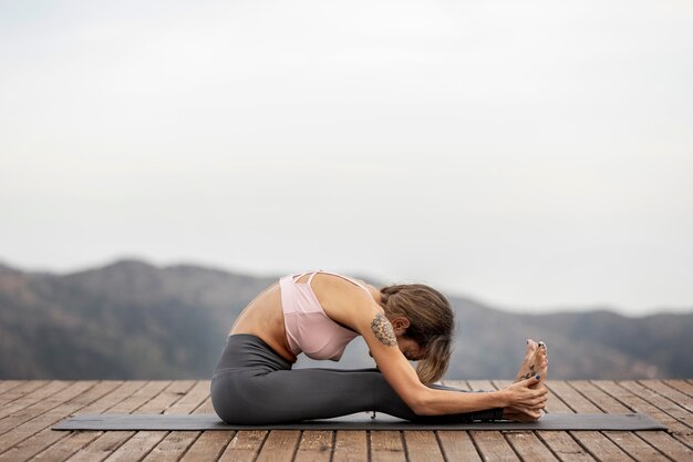 Side view of woman doing yoga outdoors on mat