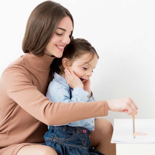 Side view of woman drawing with little girl