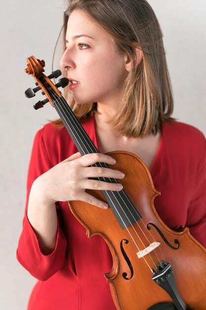 Side view of woman in dress posing while holding violin