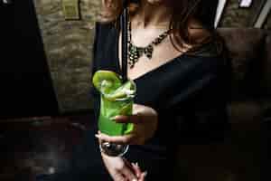 Бесплатное фото Вид сбоку женщина пьет освежающий коктейль из киви